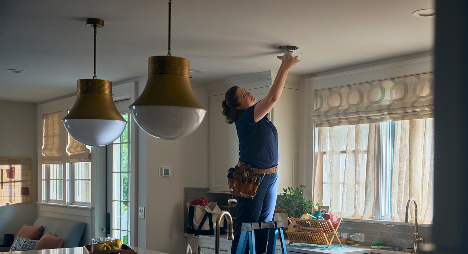 A professional IERNA'S electrician standing on a ladder to install modern recessed ceiling lights during a residential electrical installation service.