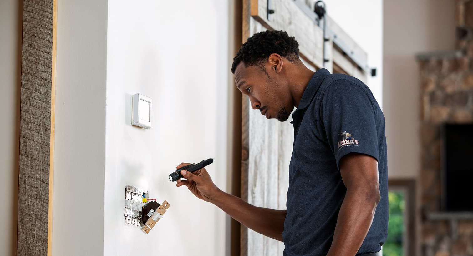 A professional IERNA'S electrician using a flashlight to safely inspect and troubleshoot exposed residential wall switch wiring during an electrical repair service.