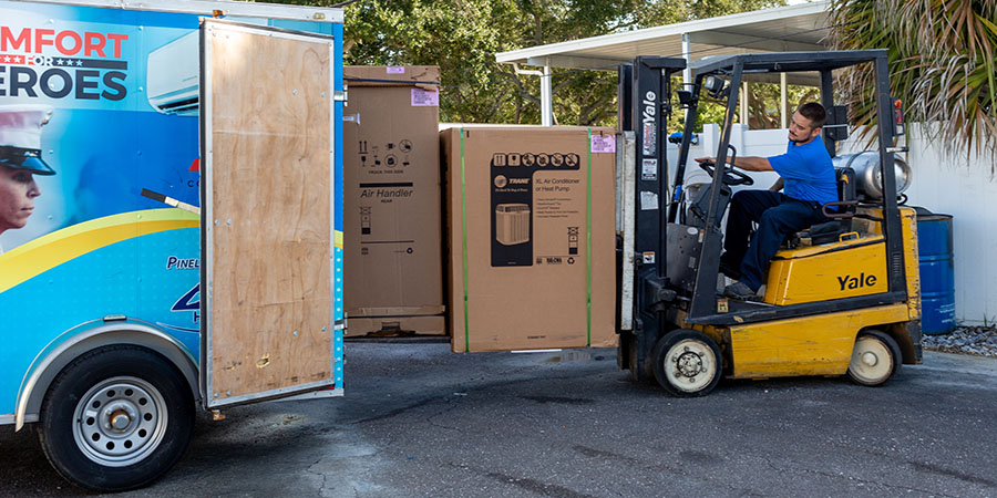 Pinellas Comfort System's technician loading trailer with new hvac equipment